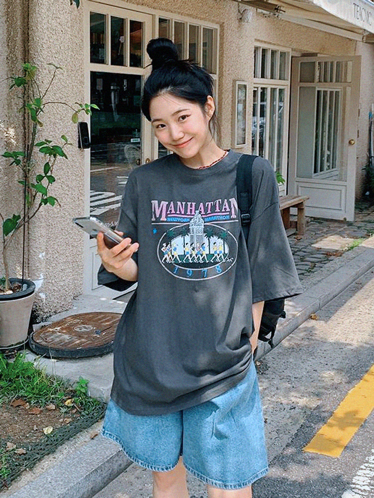Woman in oversized Manhattan graphic t-shirt and light-wash Bermuda shorts