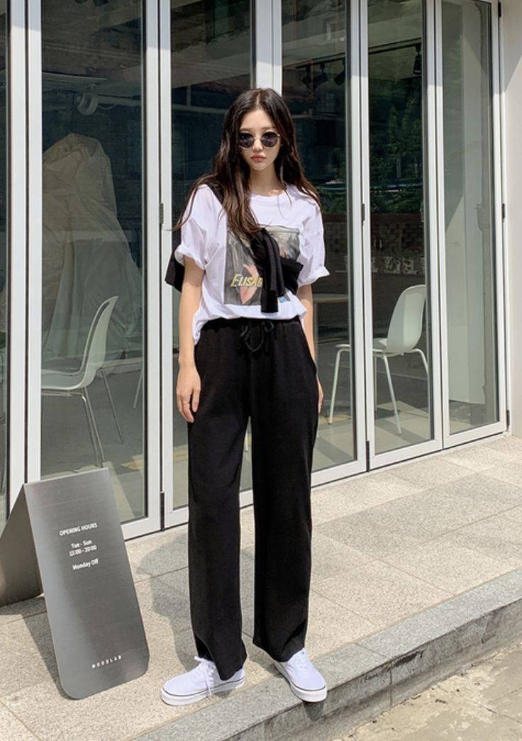 Woman in white tee, black wide pants and draped knit top street style