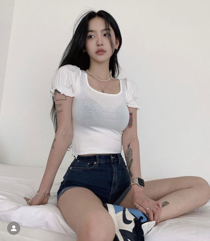 Woman wearing white puff-sleeve crop top and high-waist denim shorts
