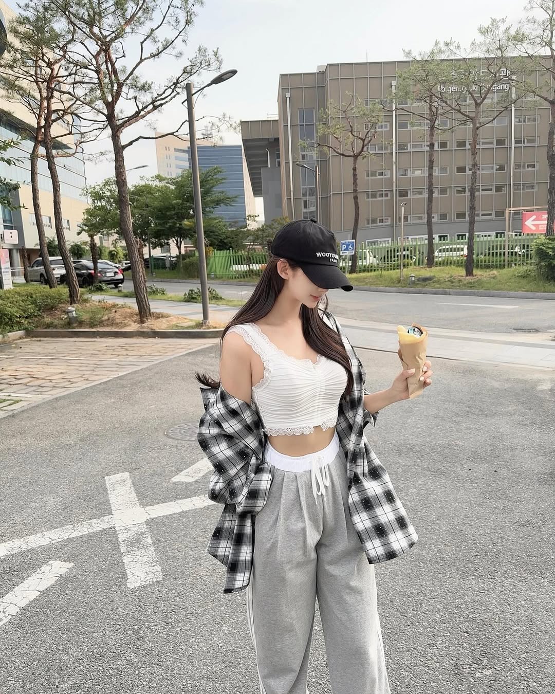 Woman wearing check shirt, white lace crop top, and gray jogger pants in casual outfit
