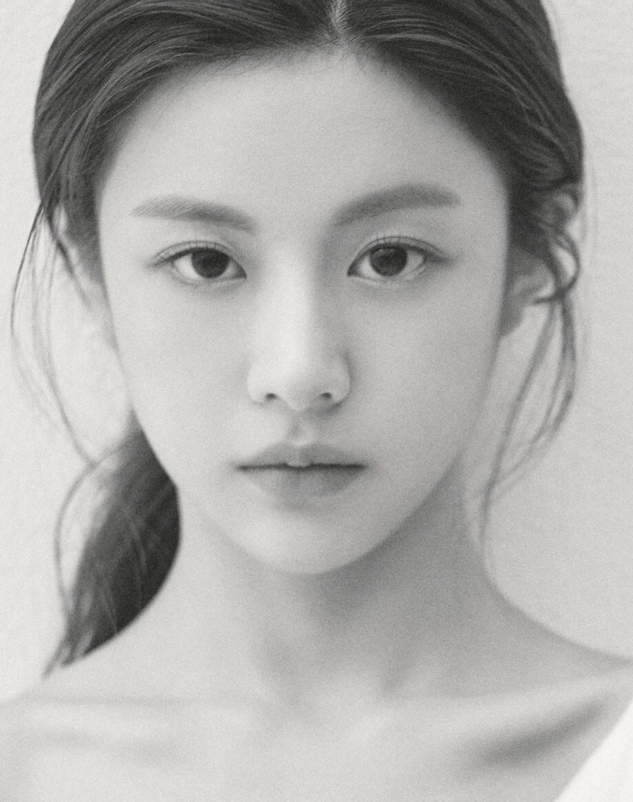 A black-and-white portrait of a woman with tied-back hair looking forward