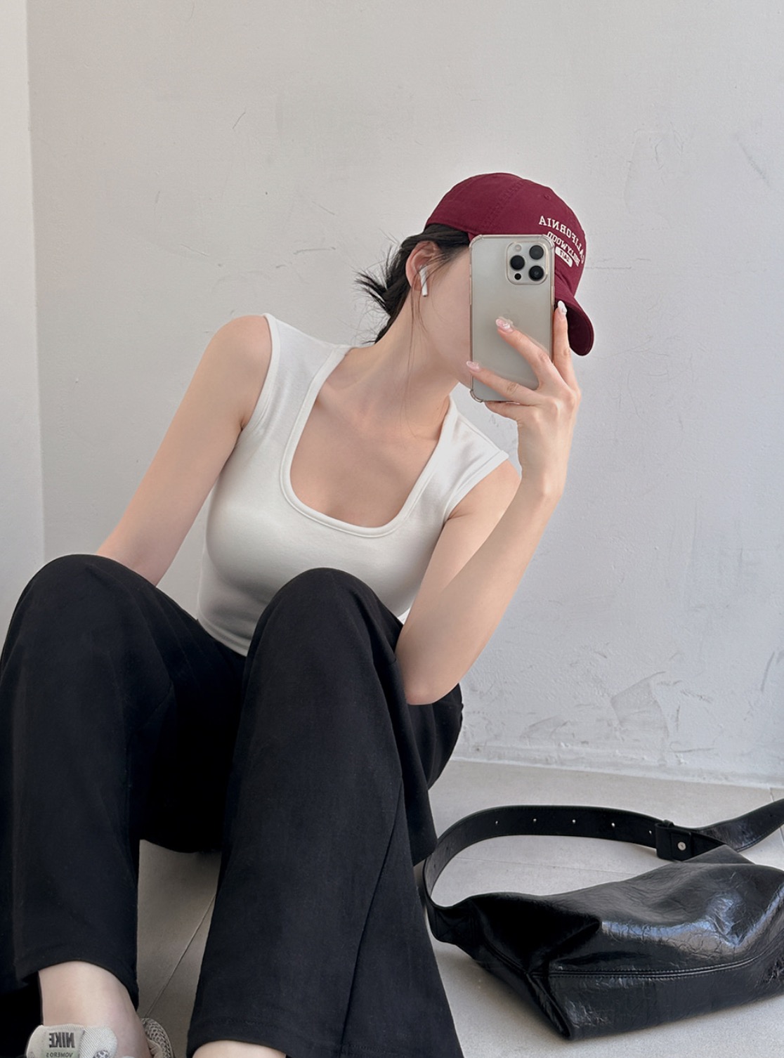 Woman wearing burgundy cap, square-neck sleeveless top, and black pants