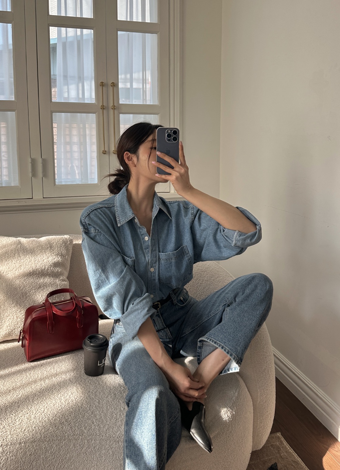 Woman wearing denim shirt and jeans with red bag and loafers