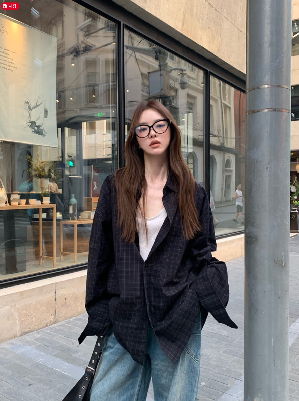 Woman in check shirt and wide jeans with glasses on the street