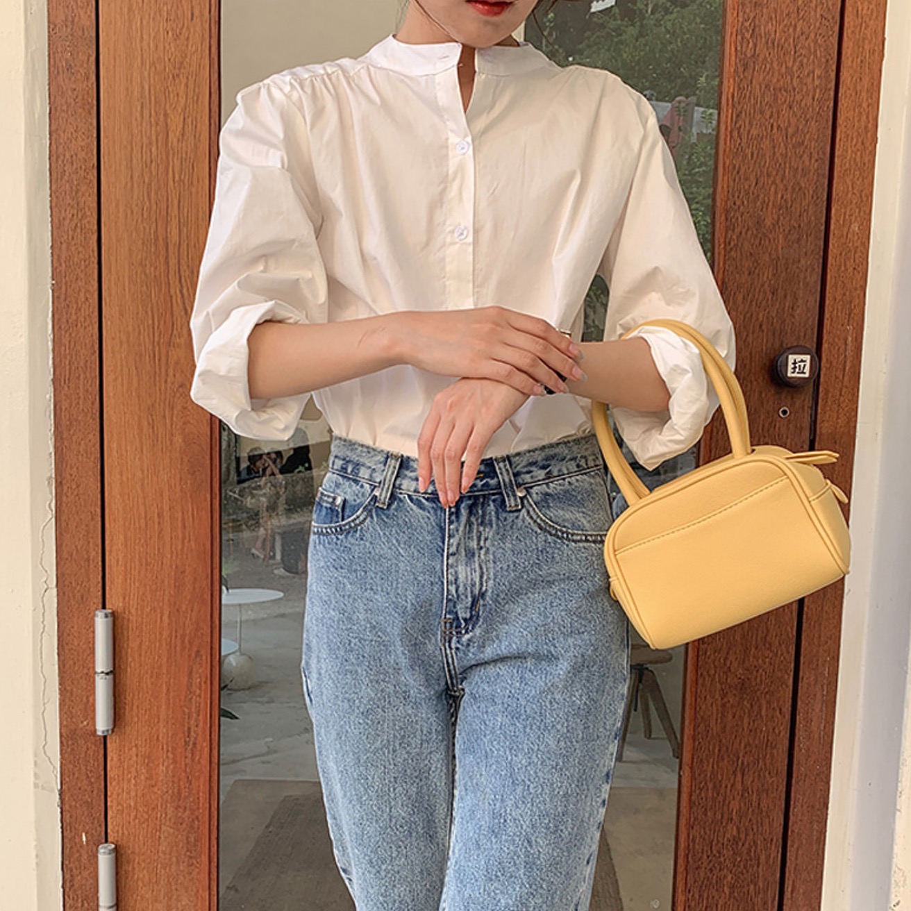 Woman in white shirt and denim jeans holding yellow mini bag