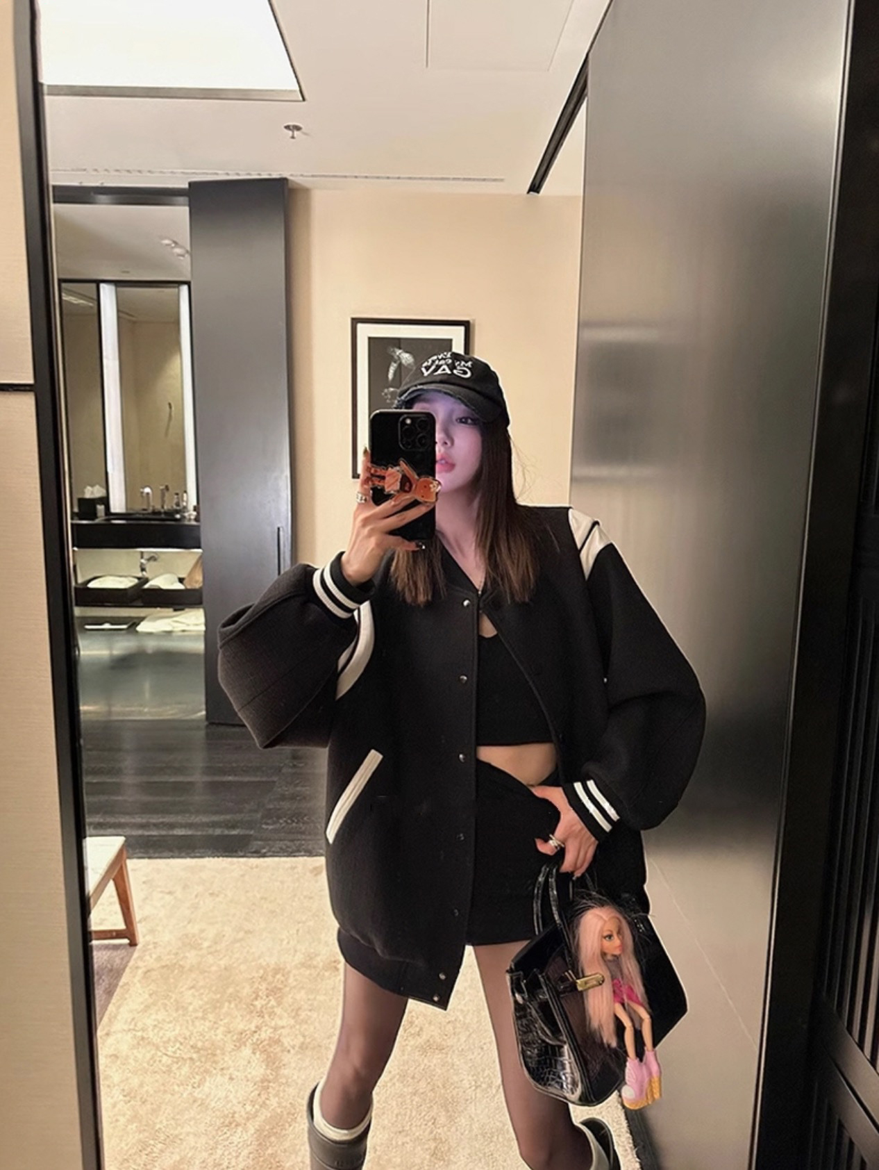 Woman in black streetwear outfit with Barbie doll bag charm